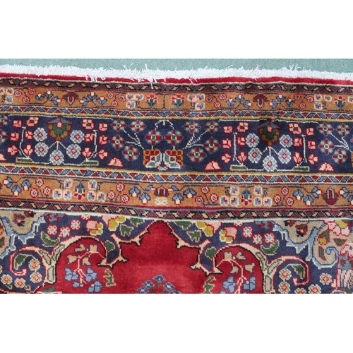 2131 - A RED GROUND TABRIZ RUGwith dark blue and beige flower head central medallion, matching spandrels an... 