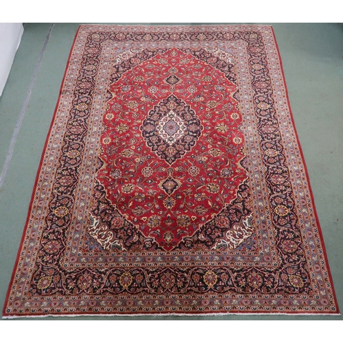 2132 - A RED GROUND KASHAN RUG With dark blue and cream diamond central medallion and matching spandrels on... 