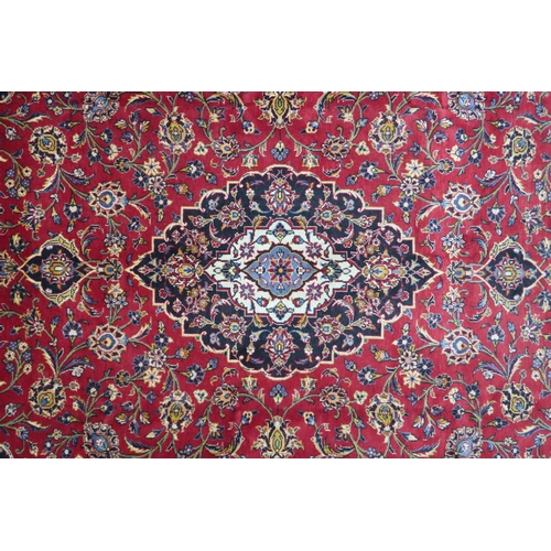 2132 - A RED GROUND KASHAN RUG With dark blue and cream diamond central medallion and matching spandrels on... 