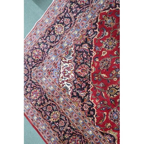 2132 - A RED GROUND KASHAN RUG With dark blue and cream diamond central medallion and matching spandrels on... 