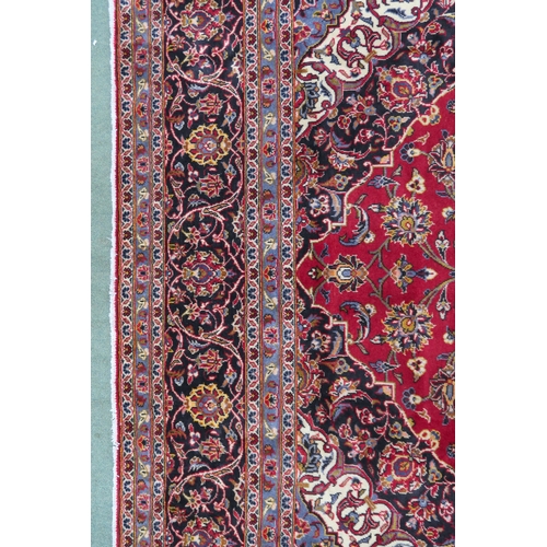 2132 - A RED GROUND KASHAN RUG With dark blue and cream diamond central medallion and matching spandrels on... 