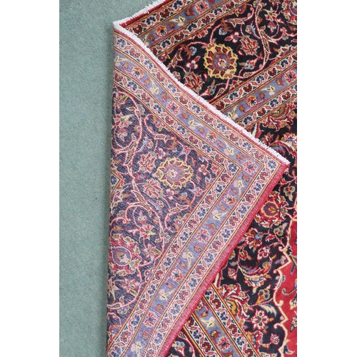 2132 - A RED GROUND KASHAN RUG With dark blue and cream diamond central medallion and matching spandrels on... 