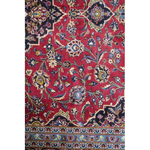 2132 - A RED GROUND KASHAN RUG With dark blue and cream diamond central medallion and matching spandrels on... 