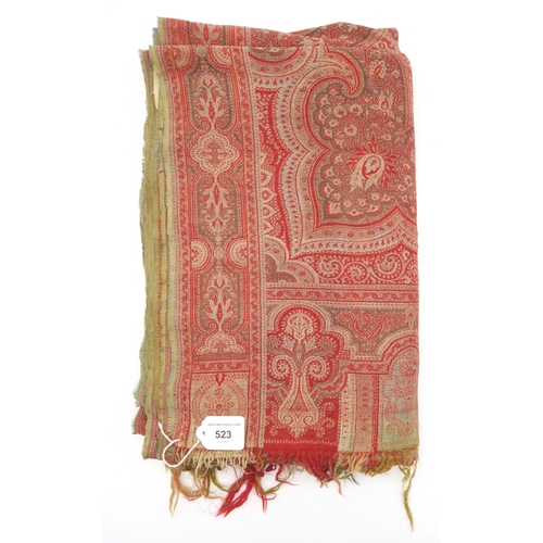 523 - A Paisley shawl, woven in hues of red, measuring approx. 329cm x 154cm