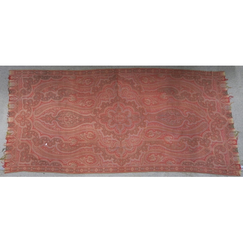 523 - A Paisley shawl, woven in hues of red, measuring approx. 329cm x 154cm