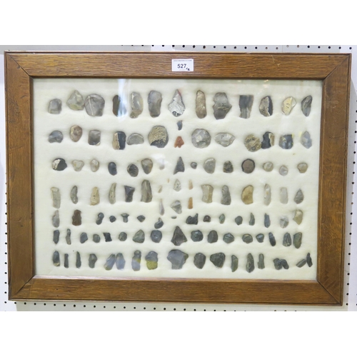 527 - A wall-mounted cased display of flint arrow/spearheads and other tools, measuring approx. 62cm x 46c... 