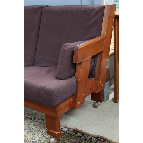 69 - A mid 20th century teak framed three seater settee with stylized angular backrest and arms on chamfe... 