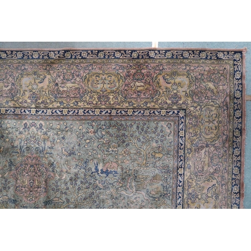 70 - A green ground Axminster style rug with beige central medallion on ground decorated trees and styliz... 