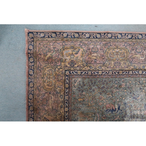 70 - A green ground Axminster style rug with beige central medallion on ground decorated trees and styliz... 