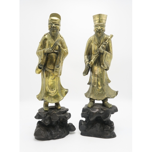 2374 - A PAIR OF CHINESE BRASS OFFICIALSEach standing and holding an object on a high rocky mound base,58cm... 