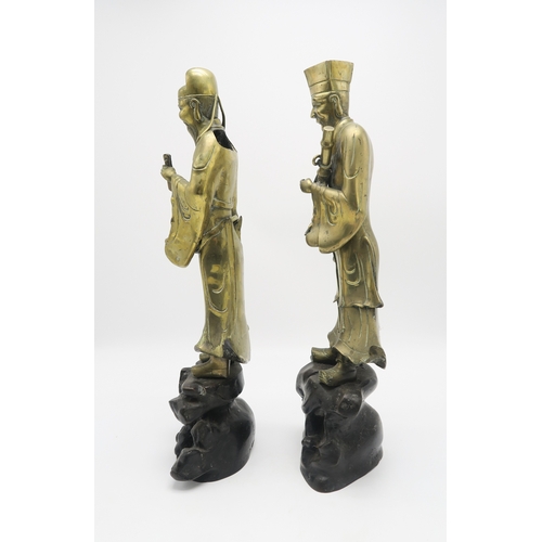 2374 - A PAIR OF CHINESE BRASS OFFICIALSEach standing and holding an object on a high rocky mound base,58cm... 