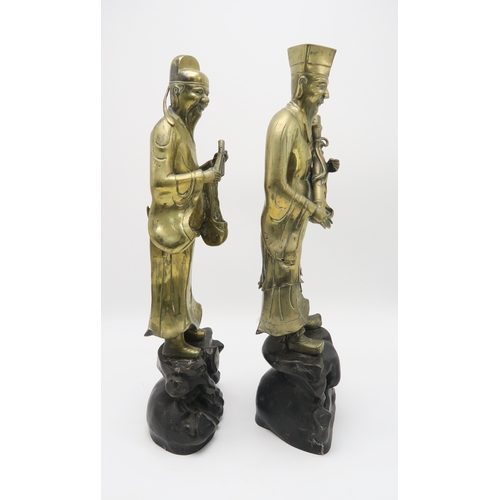 2374 - A PAIR OF CHINESE BRASS OFFICIALSEach standing and holding an object on a high rocky mound base,58cm... 