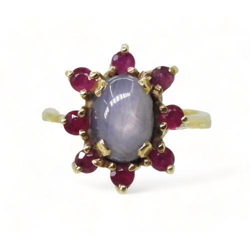 2758 - A RUBY AND STAR SAPPHIRE RINGset in bright yellow metal stamped 750, the centre of the flower cluste... 