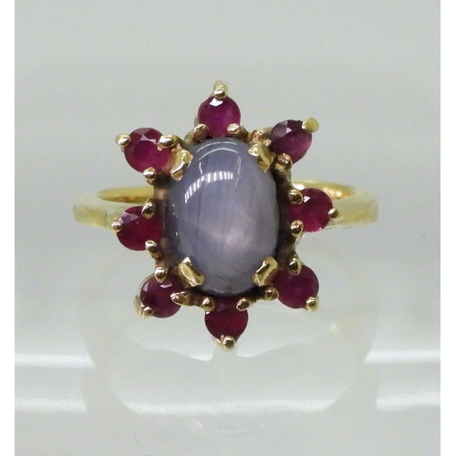 2758 - A RUBY AND STAR SAPPHIRE RINGset in bright yellow metal stamped 750, the centre of the flower cluste... 