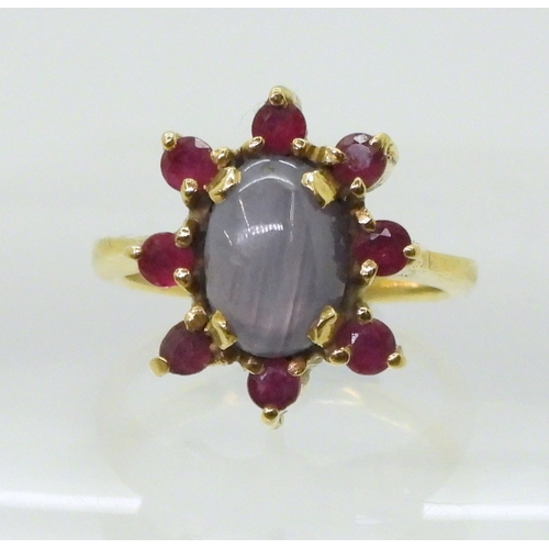 2758 - A RUBY AND STAR SAPPHIRE RINGset in bright yellow metal stamped 750, the centre of the flower cluste... 