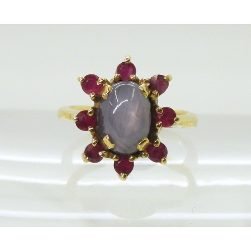 2758 - A RUBY AND STAR SAPPHIRE RINGset in bright yellow metal stamped 750, the centre of the flower cluste... 