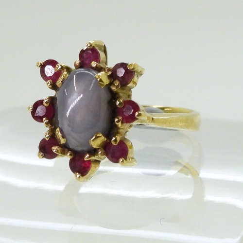 2758 - A RUBY AND STAR SAPPHIRE RINGset in bright yellow metal stamped 750, the centre of the flower cluste... 