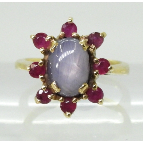 2758 - A RUBY AND STAR SAPPHIRE RINGset in bright yellow metal stamped 750, the centre of the flower cluste... 