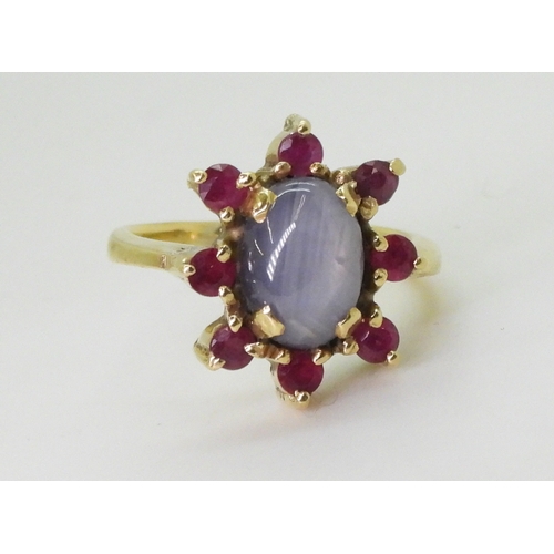 2758 - A RUBY AND STAR SAPPHIRE RINGset in bright yellow metal stamped 750, the centre of the flower cluste... 