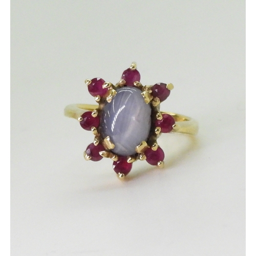 2758 - A RUBY AND STAR SAPPHIRE RINGset in bright yellow metal stamped 750, the centre of the flower cluste... 