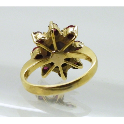 2758 - A RUBY AND STAR SAPPHIRE RINGset in bright yellow metal stamped 750, the centre of the flower cluste... 