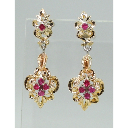 2763 - A PAIR OF CANADIAN RUBY EARRINGSthe pretty scroll mount is made in yellow and white metal and set wi... 