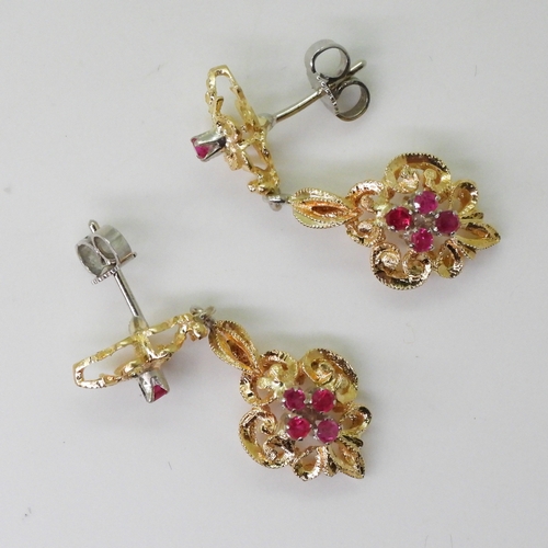 2763 - A PAIR OF CANADIAN RUBY EARRINGSthe pretty scroll mount is made in yellow and white metal and set wi... 