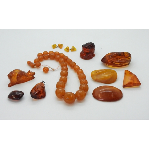 829 - A collection of amber coloured items to include, a signed cat inro, a carved snail, amber specimens,... 