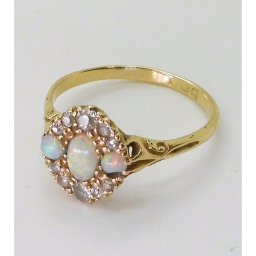 2778 - AN 18CT GOLD VINTAGE RINGset with three opals and old cut diamonds. With galleried mount and scroll ... 