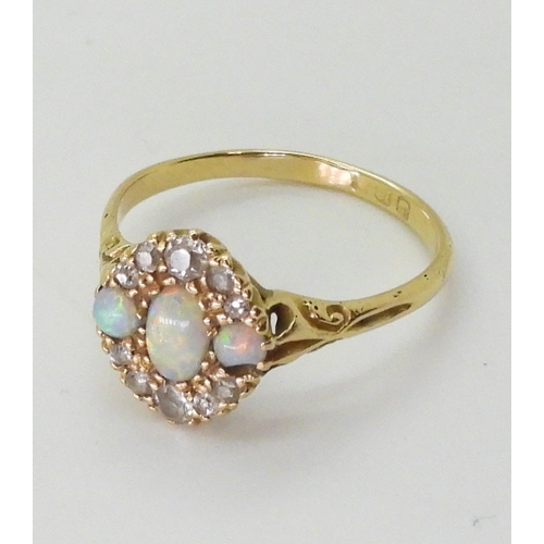 2778 - AN 18CT GOLD VINTAGE RINGset with three opals and old cut diamonds. With galleried mount and scroll ... 