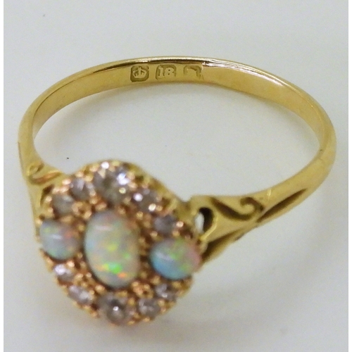 2778 - AN 18CT GOLD VINTAGE RINGset with three opals and old cut diamonds. With galleried mount and scroll ... 