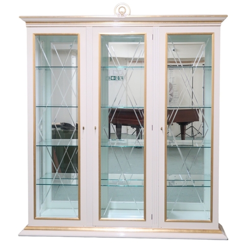 2087 - A CONTEMPORARY GILT WHITE VERSACE TRIPLE DOOR DISPLAY CABINET with moulded cornice with laurel ... 