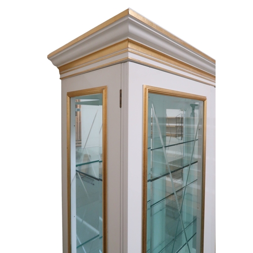 2087 - A CONTEMPORARY GILT WHITE VERSACE TRIPLE DOOR DISPLAY CABINET with moulded cornice with laurel ... 