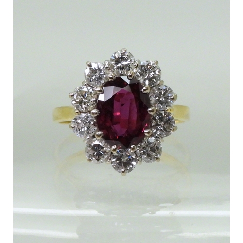 2786 - A RUBY AND DIAMOND CLUSTER RINGmounted in a classic 18ct gold basket mount, set with a oval cut ruby... 