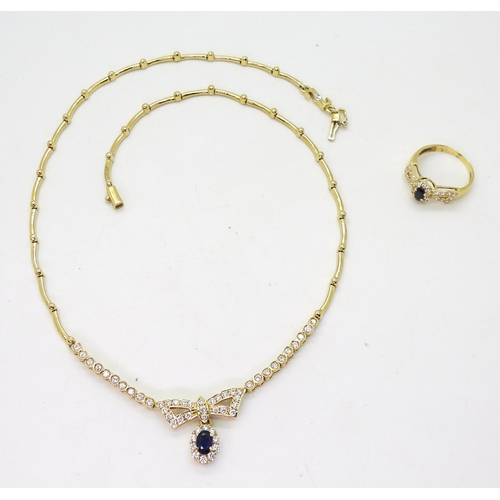 2801 - AN ARABIC GOLD NECKLACE AND RINGset with blue and clear gems to the bow motif, length of necklace ap... 