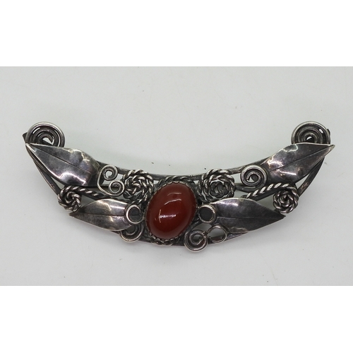 2815 - TWO ARTS & CRAFTS JEWELSa silver carnelian brooch in the style of Mary Thew, with applied leaves... 