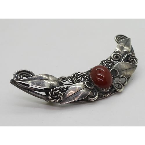 2815 - TWO ARTS & CRAFTS JEWELSa silver carnelian brooch in the style of Mary Thew, with applied leaves... 