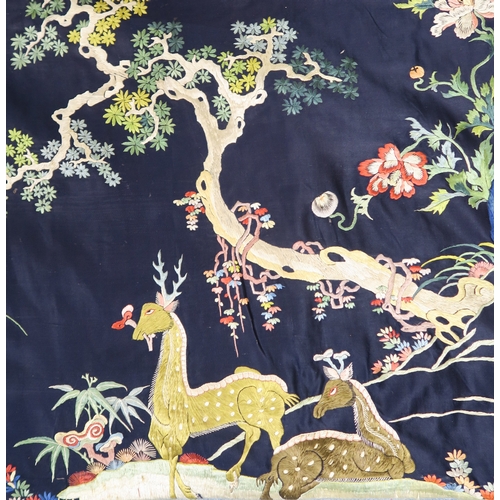 2397 - A CHINESE BLUE GROUND SILK EMBROIDERED PANELdepicting cranes and deer amongst peaches, pine trees, p... 