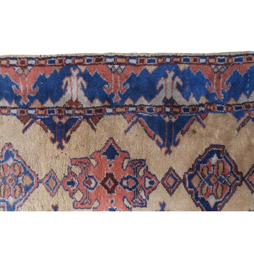 2140 - A LARGE BEIGE GROUND MALAYER RUNNER with multicoloured medallions and geometric borders, 647cm ... 