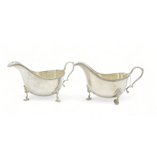 362 - A pair of silver sauceboats, by Mappin & Webb, Sheffield 1957, with an anthemion-capped scroll h... 