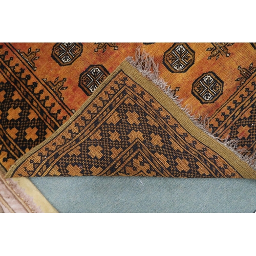 125 - An amber ground Bokhara style rug with all over lozenge design within geometric borders, 260cm long ... 