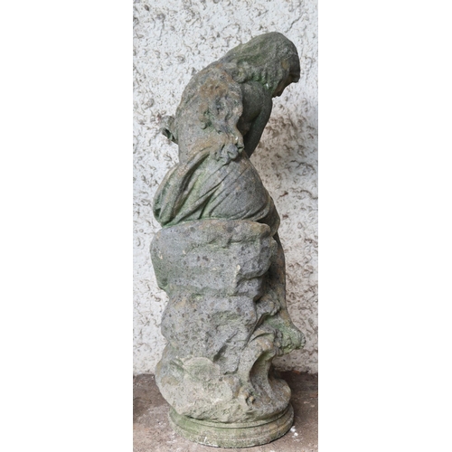 150 - A 20th century reconstituted stone garden statue depicting a nude bather reclining on rocks, 85cm hi... 