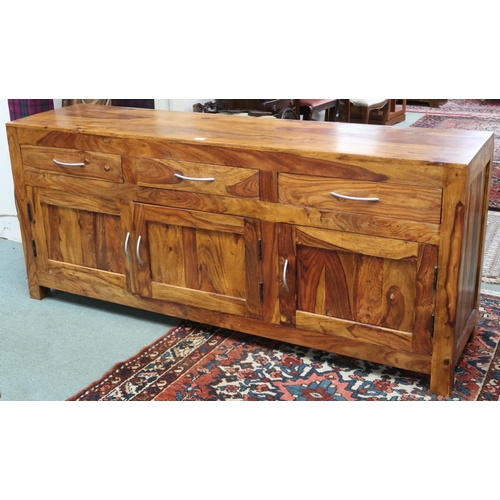 89 - A contemporary mangowood sideboard with three drawers over three panel cabinet doors on square feet,... 