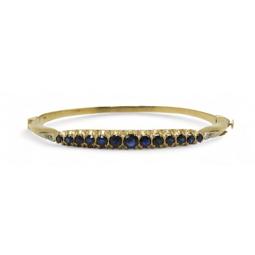 A Sapphire and diamond bangle with 9ct gold hallmarks for London 1987. Inner diameter 5.7cm x 5.2cm, weight 13gms