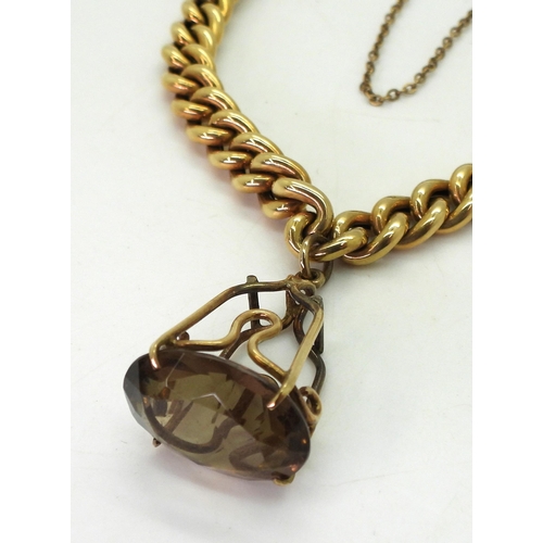 714 - A 14k gold gold curb chain bracelet, with an attached smoky quartz and yellow metal pendant, weight ... 