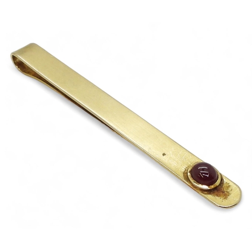 766 - A yellow metal tie slide set with a cabochon ruby weight 11.2gms