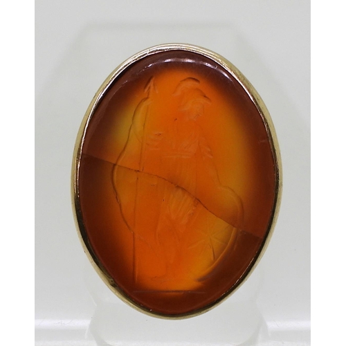 792 - A bright yellow metal signet ring set with a large carnelian intaglio carved with Brittania (cracked... 