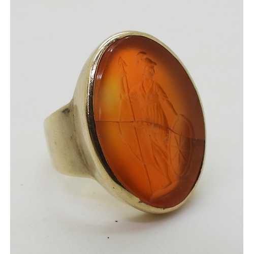 792 - A bright yellow metal signet ring set with a large carnelian intaglio carved with Brittania (cracked... 