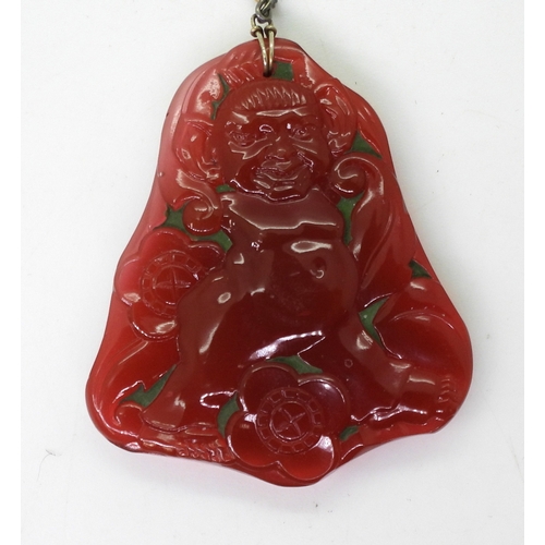 2740 - AN ART DECO PRESSED GLASS PENDANTin dark pink glass, depicting a troll character, with big ears amon... 