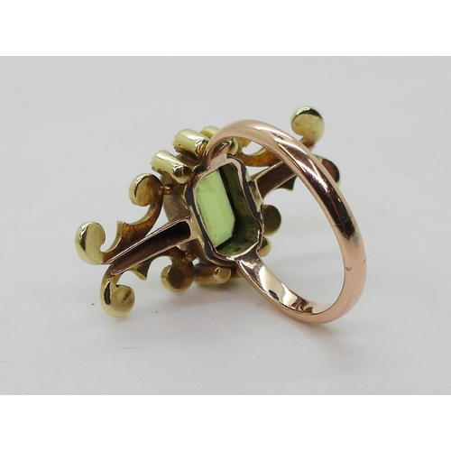 2748 - A VINTAGE PERIDOT & PEARL RINGwith an unusual linear scrolled design, the bright yellow metal he... 